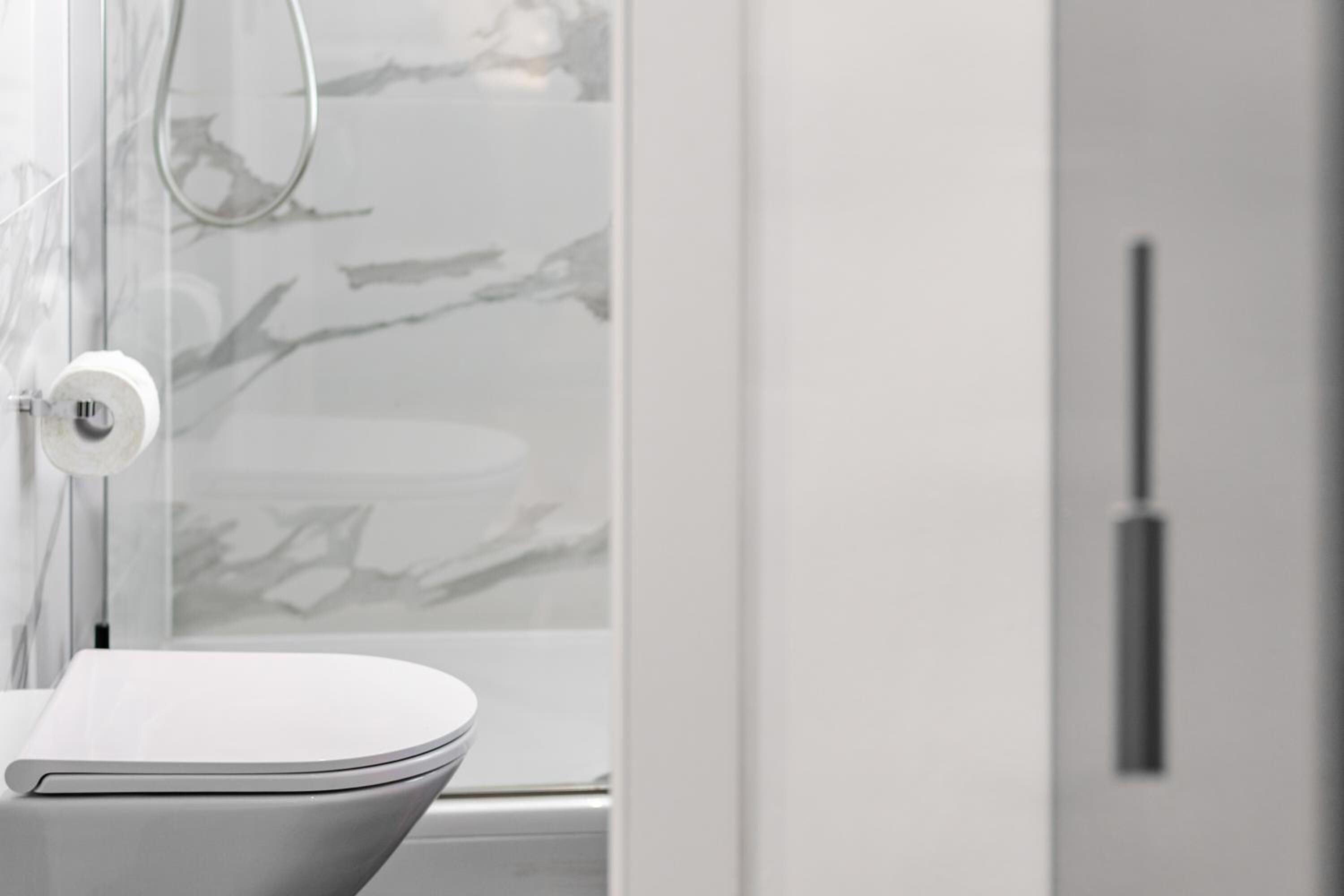 Une salle de bain moderne avec des toilettes, une douche à parois de verre et un pare-baignoire en marbre.