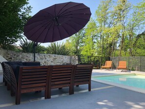 Una piscina al aire libre, sombrillas, sillones reclinables de piscina