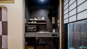 A compact kitchen with a built-in dishwasher, a microwave, and a sink. - RESI STAY Yasaka-An (Kyoto)