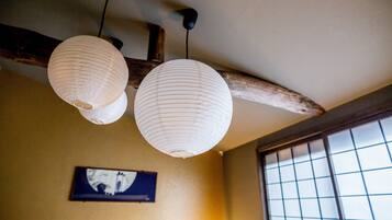 A traditional interior with two hanging paper lanterns, a wooden beam ceiling, and a framed picture on the wall.