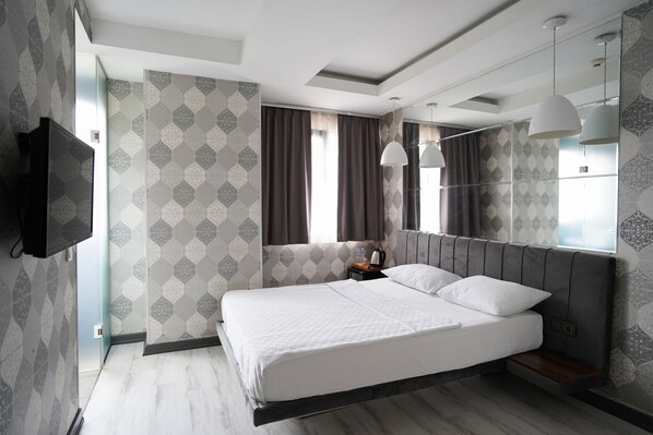 A modern hotel room with a large bed, a flat-screen TV, a bedside table with a lamp, and patterned wallpaper. - Time Hotel Mecidiyekoy (Istanbul)