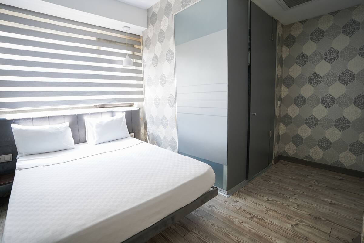 A bedroom with a bed, a wardrobe, and a patterned wall.