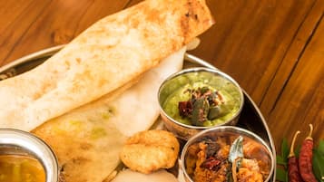 A traditional South Indian meal with dosa, idli, and various chutneys and sambar on a metal tray.