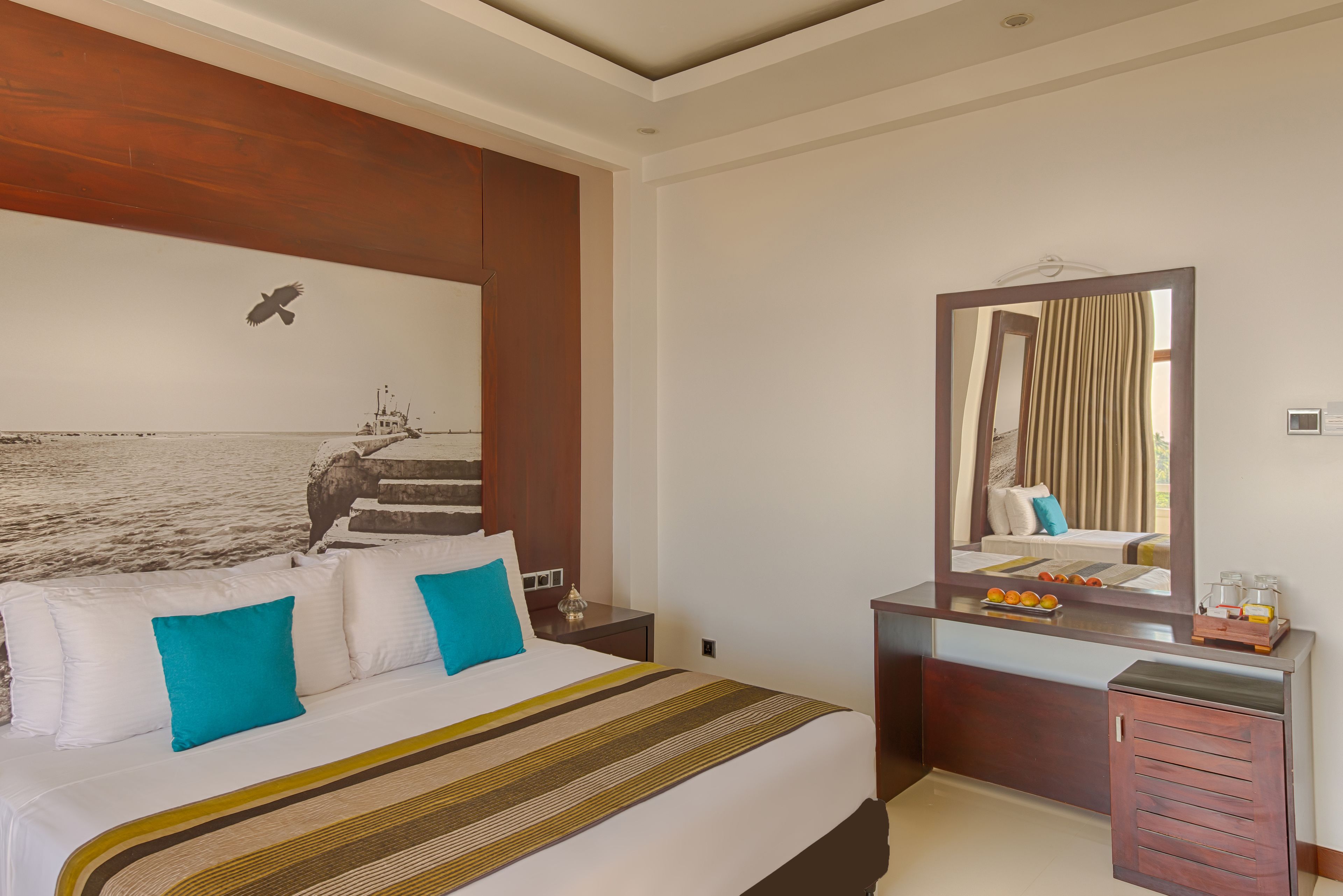 A hotel room with a large bed, a wooden headboard, a nightstand, a dresser, and a mirror.