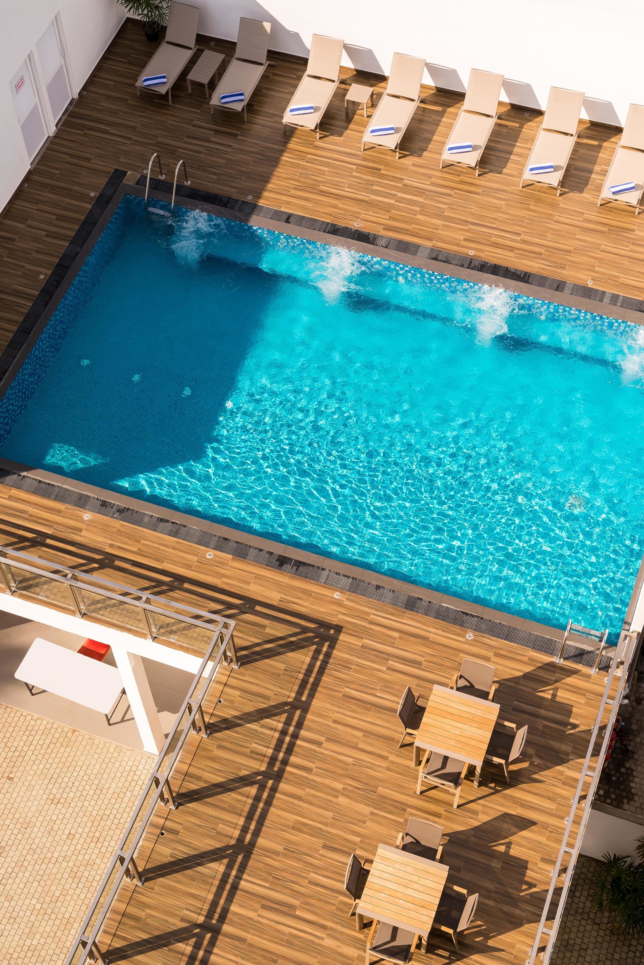 A rooftop pool with lounge chairs and a table area.
