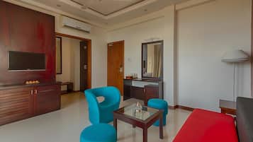 A modern living room with a flat-screen TV, a wooden cabinet, a glass-top coffee table, and a red sofa.