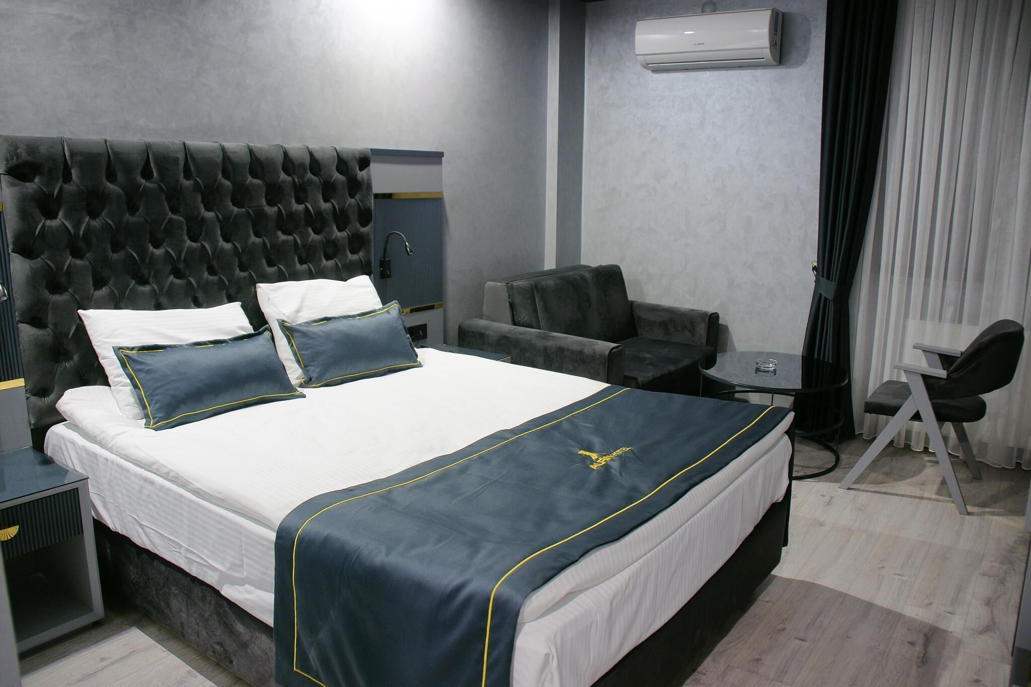 Une chambre d’hôtel avec un grand lit, un bureau, une chaise et un climatiseur fixé au mur.