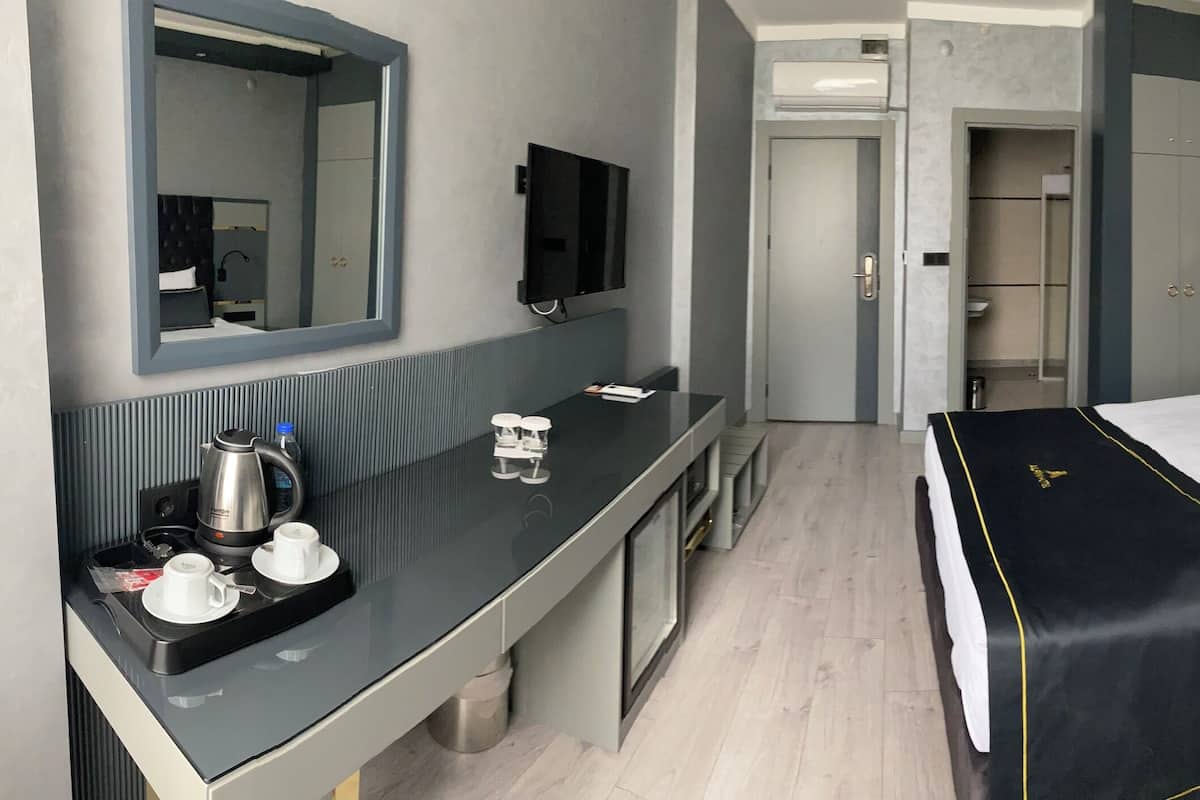 A hotel room with a bed, bedside table, TV, and a mirror.