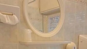A bathroom with a sink, mirror, toilet paper holder, and a tissue box. - Hotel St. Moritz (Rimini)