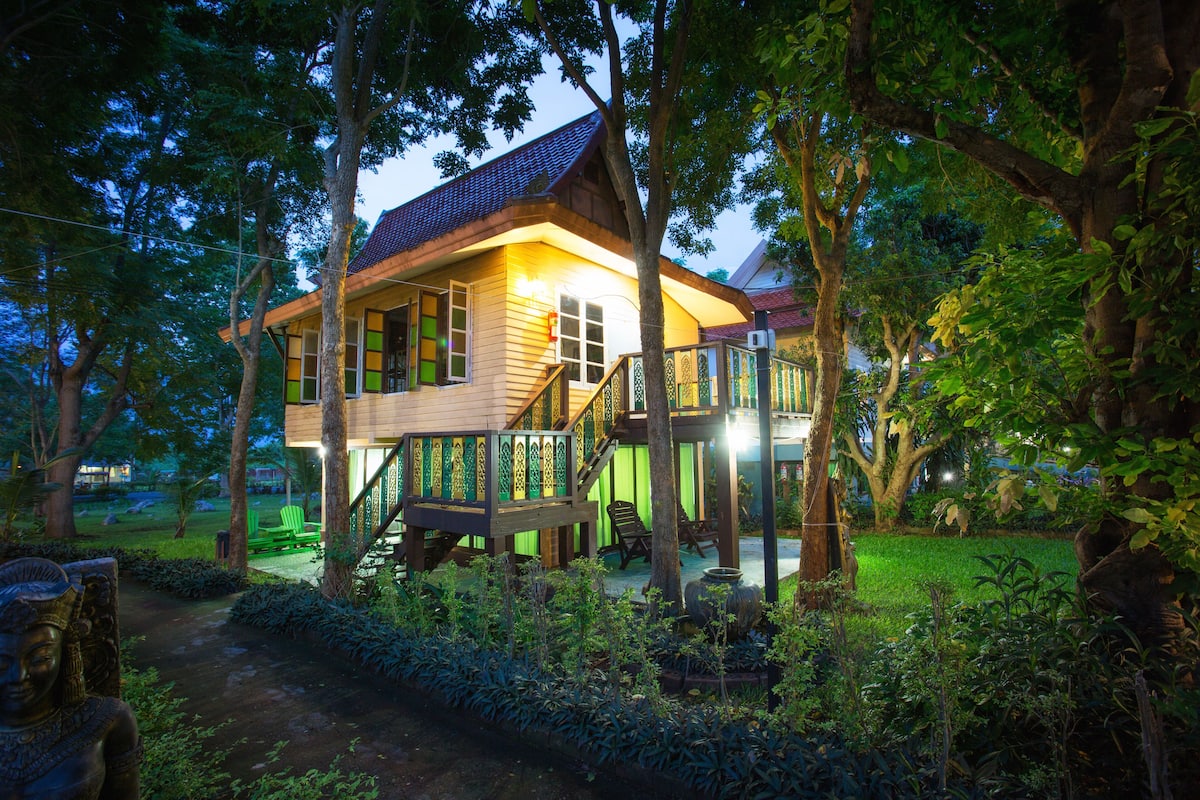 Een houten huis met balkon, omringd door bomen en groen.