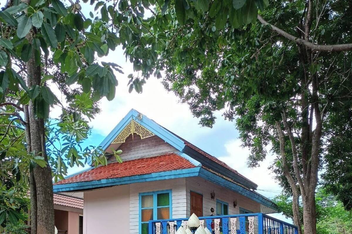 Een traditioneel huis met een pannendak, een balkon met blauwe relingen en een decoratieve omheining.