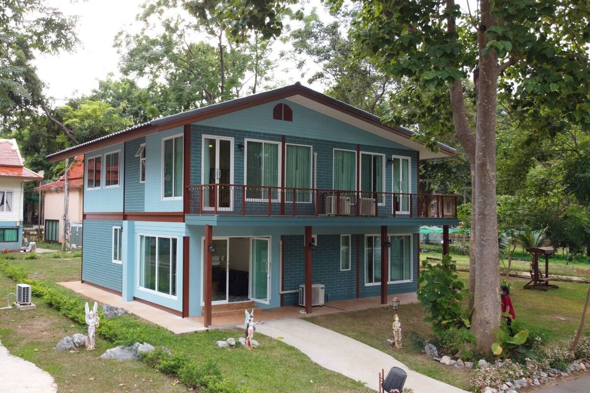Een twee verdiepingen tellend huis met een balkon, een voortuin en een kleine tuin.