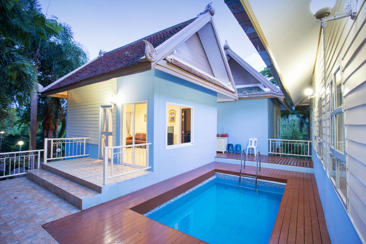 Een tweelaags huis met een zwembad, een balkon en een overdekt terras.