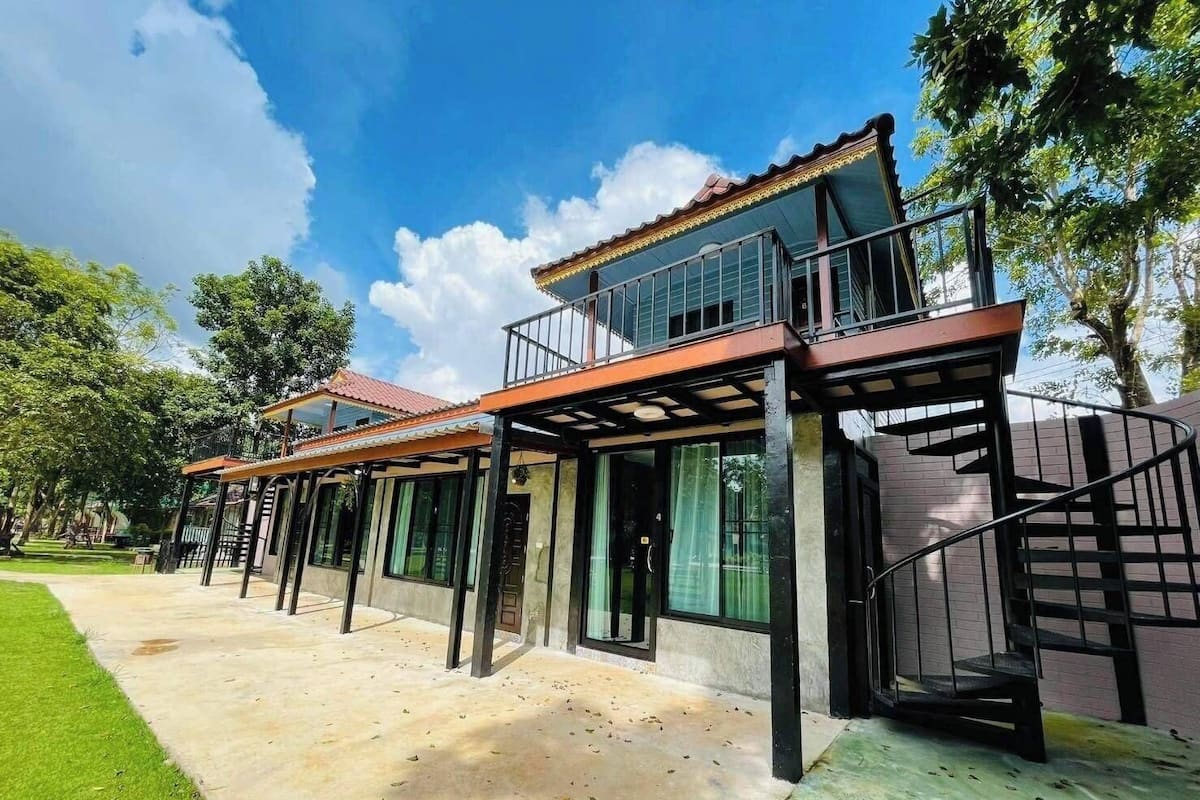 Een modern herenhuis met twee verdiepingen, een overdekt terras, een spiltrap en uitzicht op een weelderige tuin.