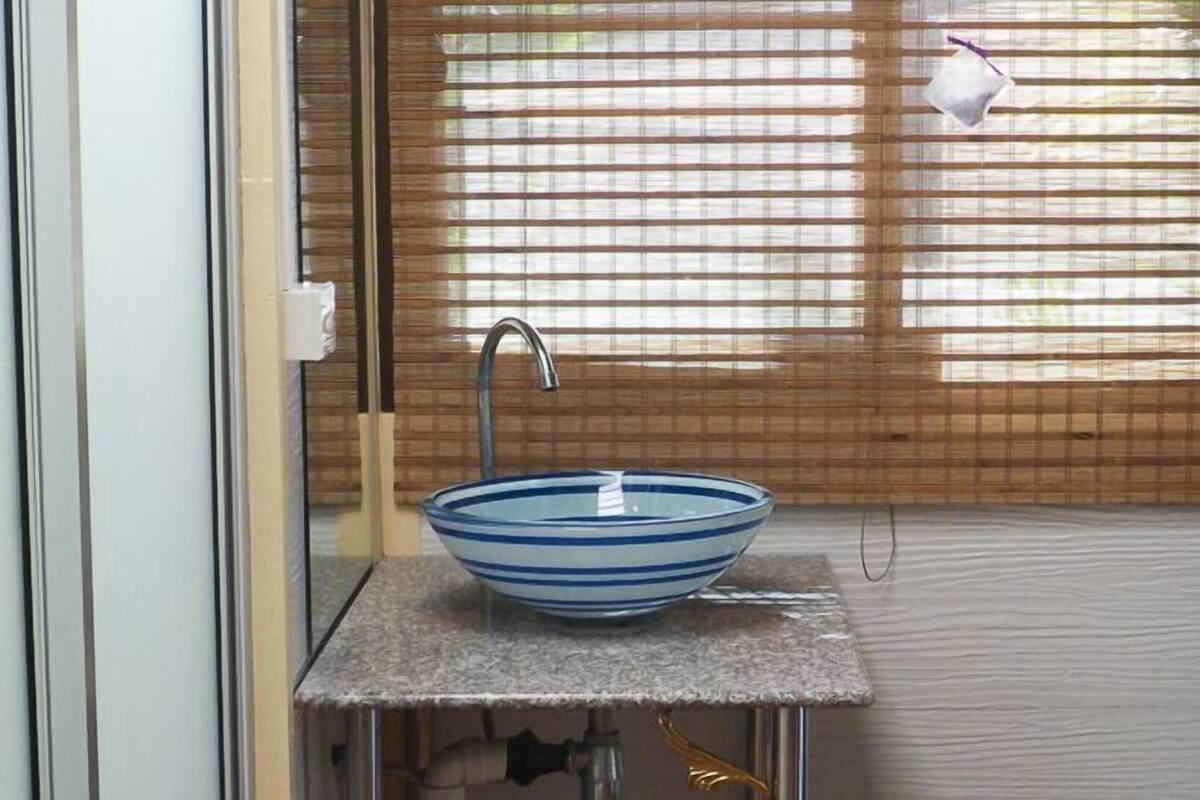 Een badkamer met een glazen wasbak, een kraan en een handdoek aan een haak.