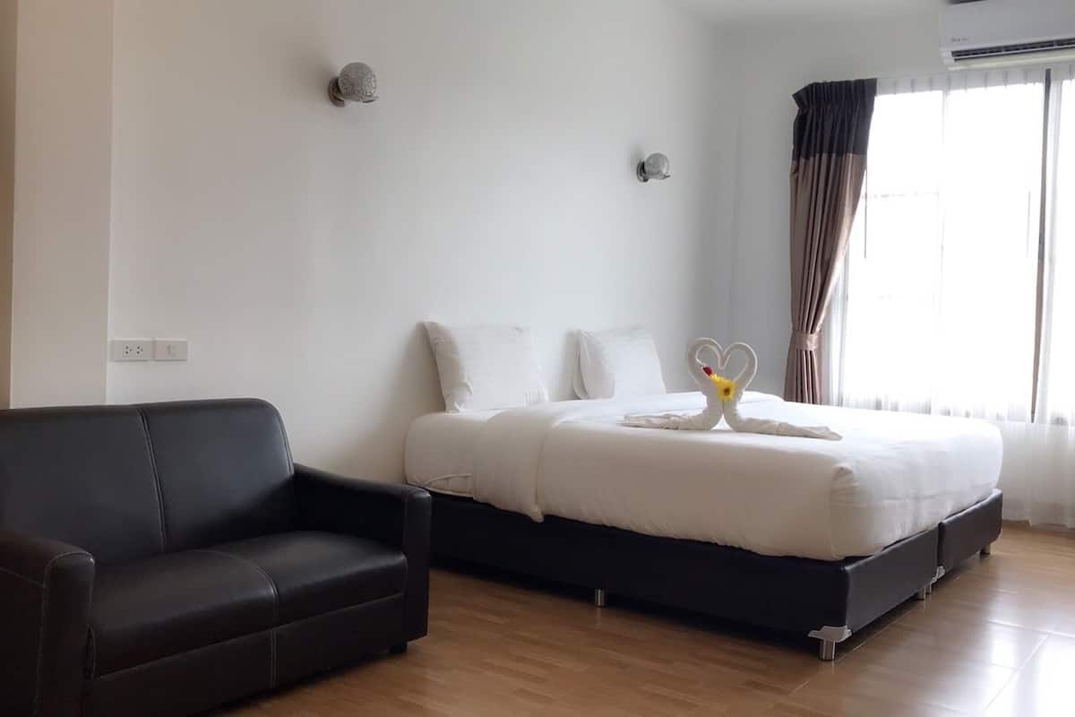 Een hotelkamer met een bed, een zwarte bank en een raam met gordijnen.
