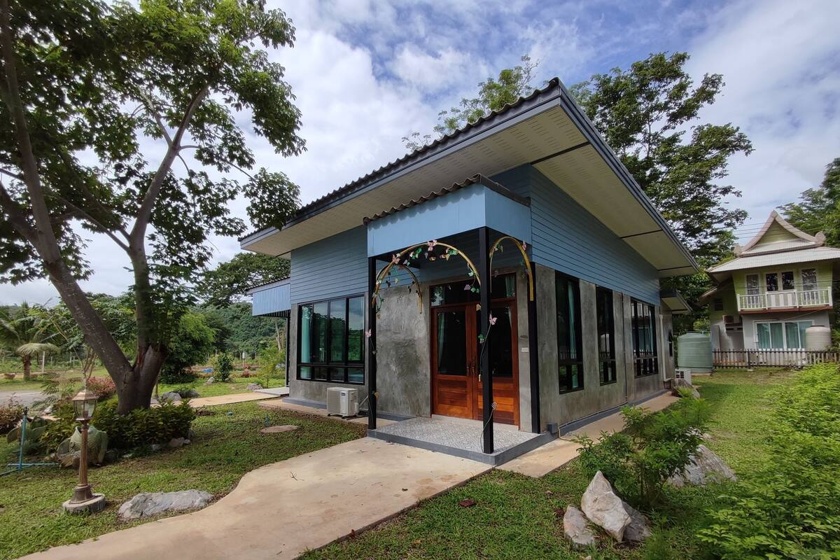 Een modern huis met een blauwe gevel, grote ramen en een verzorgde tuin.