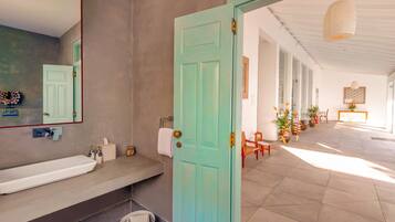 Un baño con un lavamanos grande de color blanco, un espejo y una puerta color verde azulado.