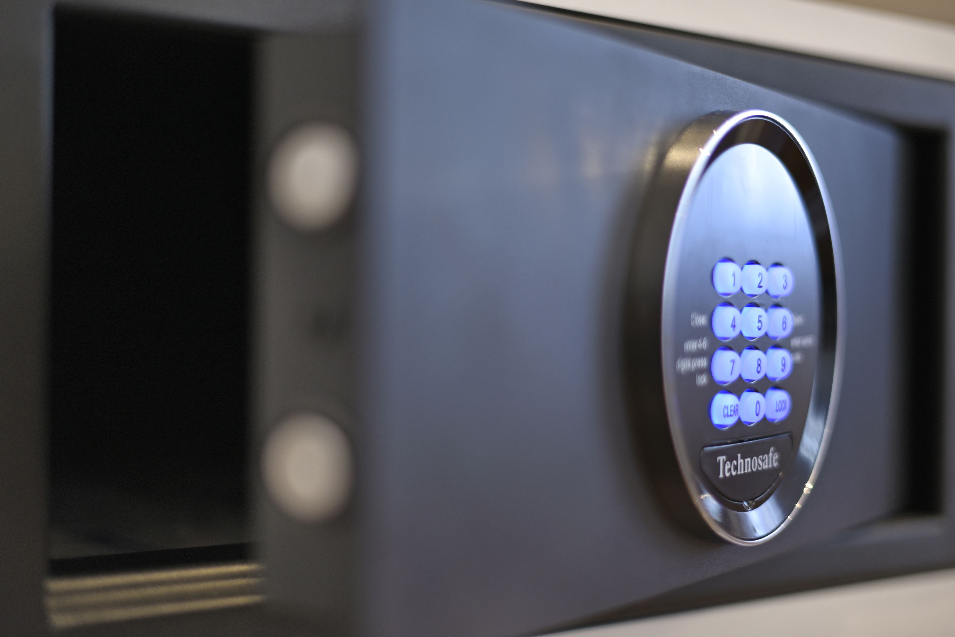 A close-up of a keypad with illuminated buttons and the brand name "Technosafe" on a metallic surface.