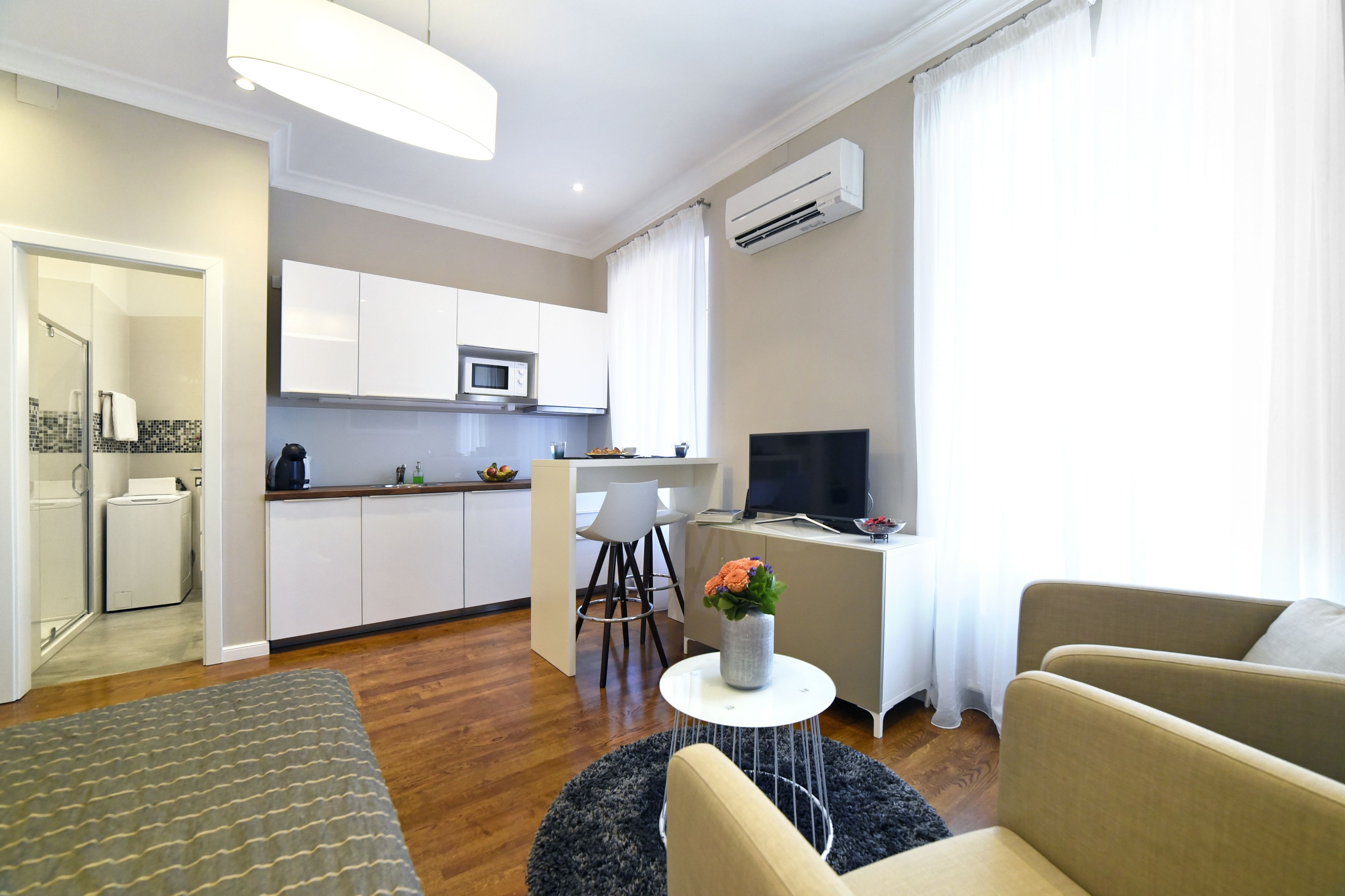 Un appartamento moderno con cucina, zona pranzo e soggiorno. Dispone di un divano, un tavolino e una TV.