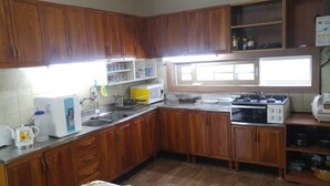 Cucina con mobili in legno, lavello, piano cottura e forno a microonde.