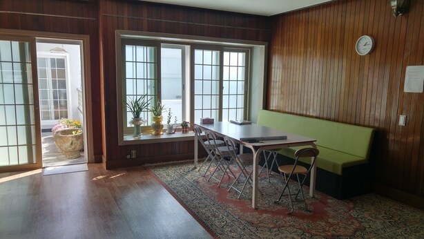 Una stanza con parete rivestita in legno, una panca verde, un tavolo da pranzo con sedie e un'ampia finestra con vista.