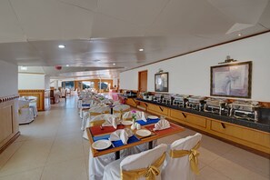 A buffet setup with multiple tables, chairs, and a counter with food stations. - Hotel Baljees Regency (Shimla)