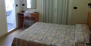 A bedroom with a bed, a desk, and a chair. - Pensione Londra (Rimini)