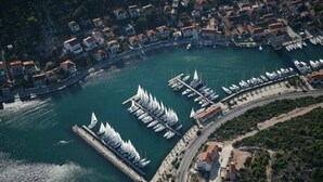 Vue aérienne d’une ville côtière avec un port de plaisance, des immeubles résidentiels et une tour imposante.