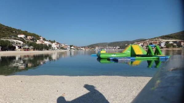 A calm waterfront with inflatable water slides and a clear sky.