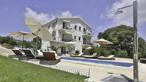 Un hôtel moderne doté d’une piscine, d’un espace extérieur aménagé et offrant une vue sur un ciel dégagé.