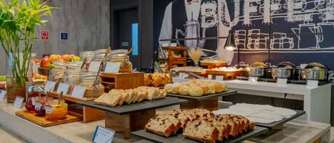 En buffé med ett varierat utbud av mat, inklusive bröd och bakverk, och en skylt som visar att det finns glutenfria alternativ.