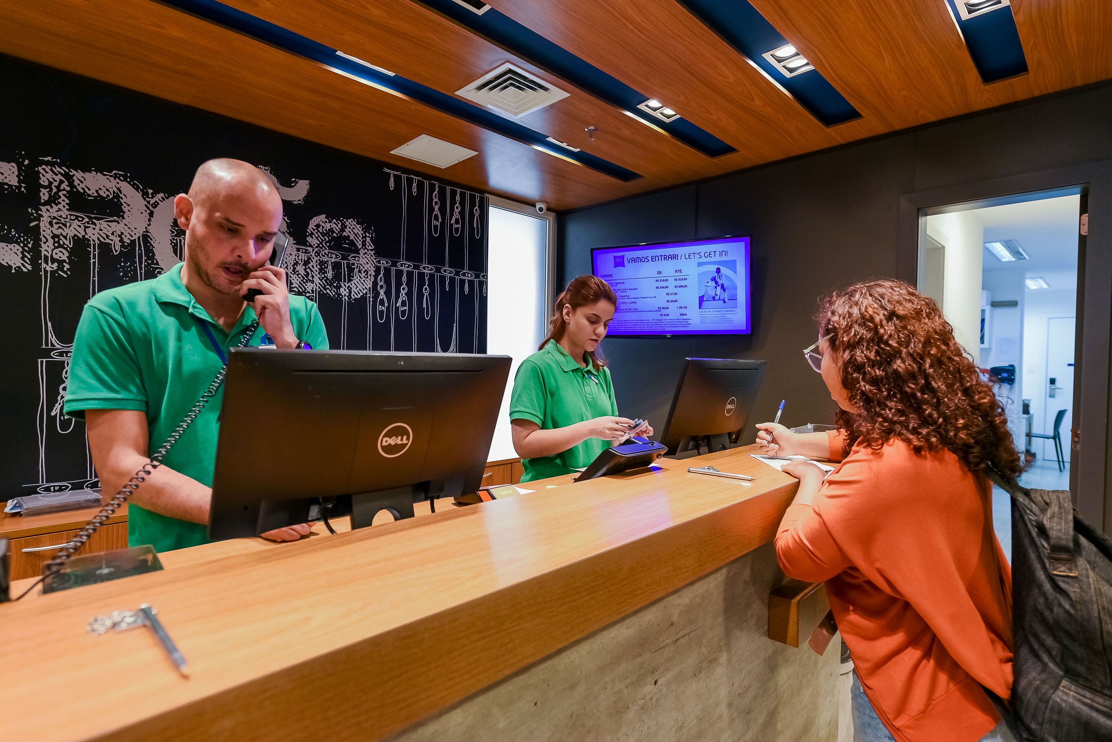 Una mesa de recepción con tres empleados, dos portátiles y un monitor.