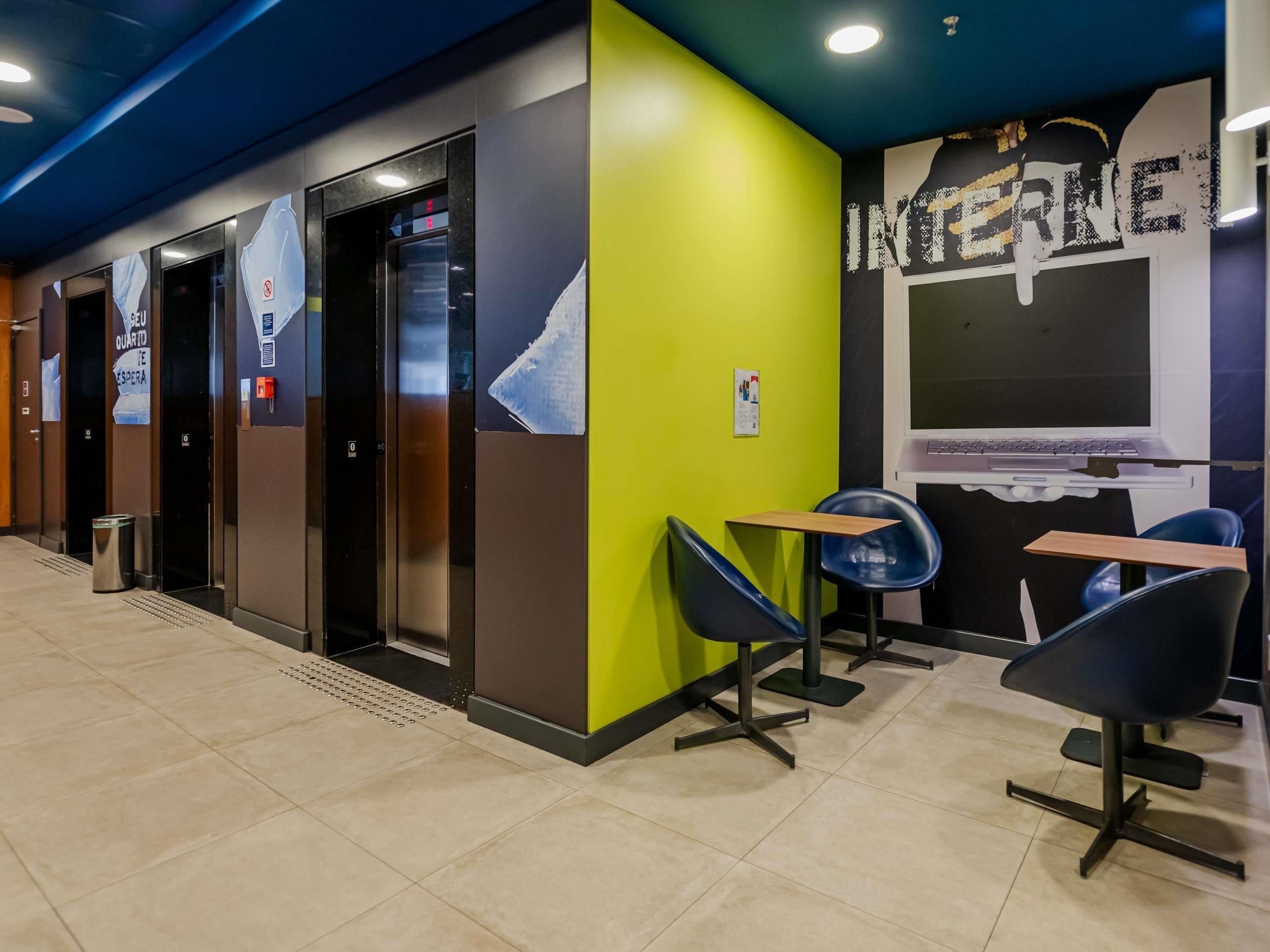 A modern interior with elevators, a bright yellow wall, and a laptop on a stand.