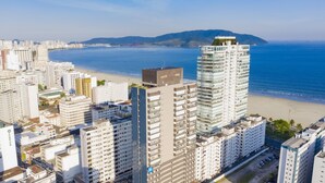 A high-rise hotel with multiple floors, a rooftop terrace, and a view of the beach and ocean.