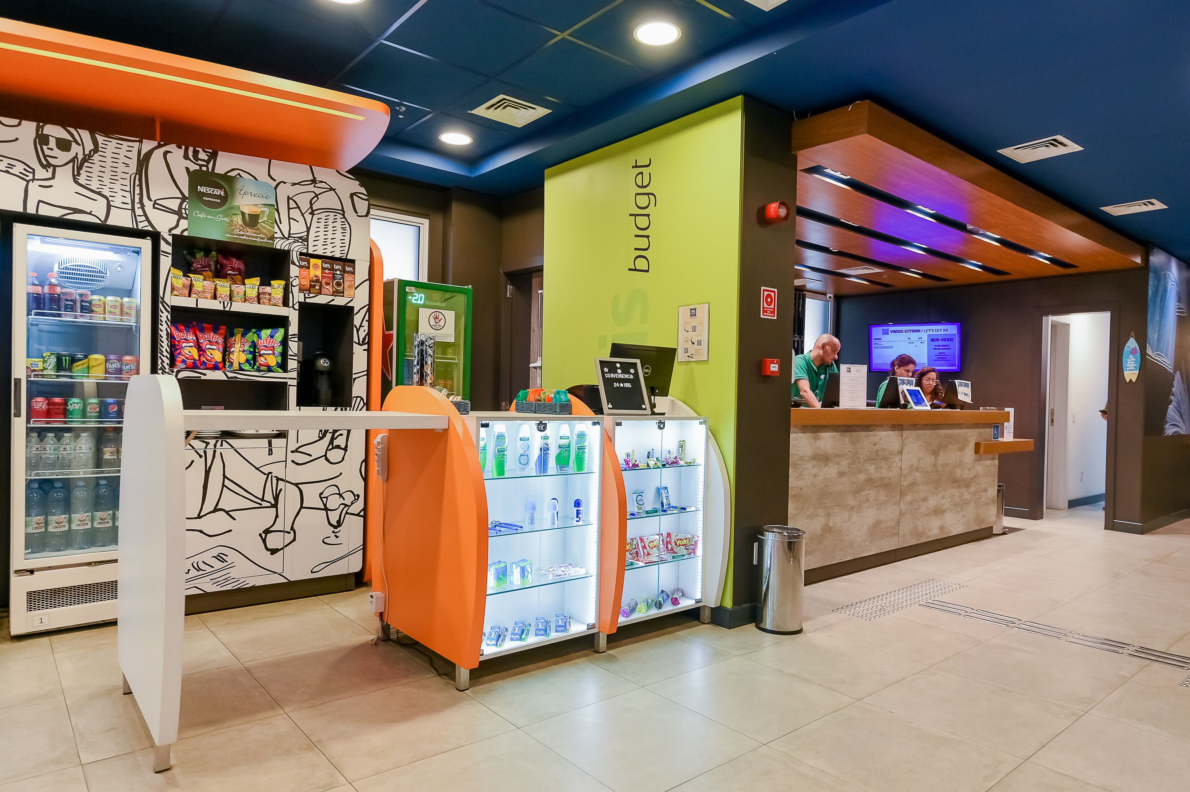 A reception area with a counter, a refrigerator stocked with snacks, and a wall with a 'budget' sign.