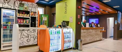 A reception area with a counter, a refrigerator stocked with snacks, and a wall with a 'budget' sign.