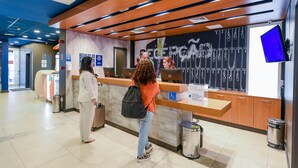 A reception area with a counter, a digital screen, and a wall with a graphic.