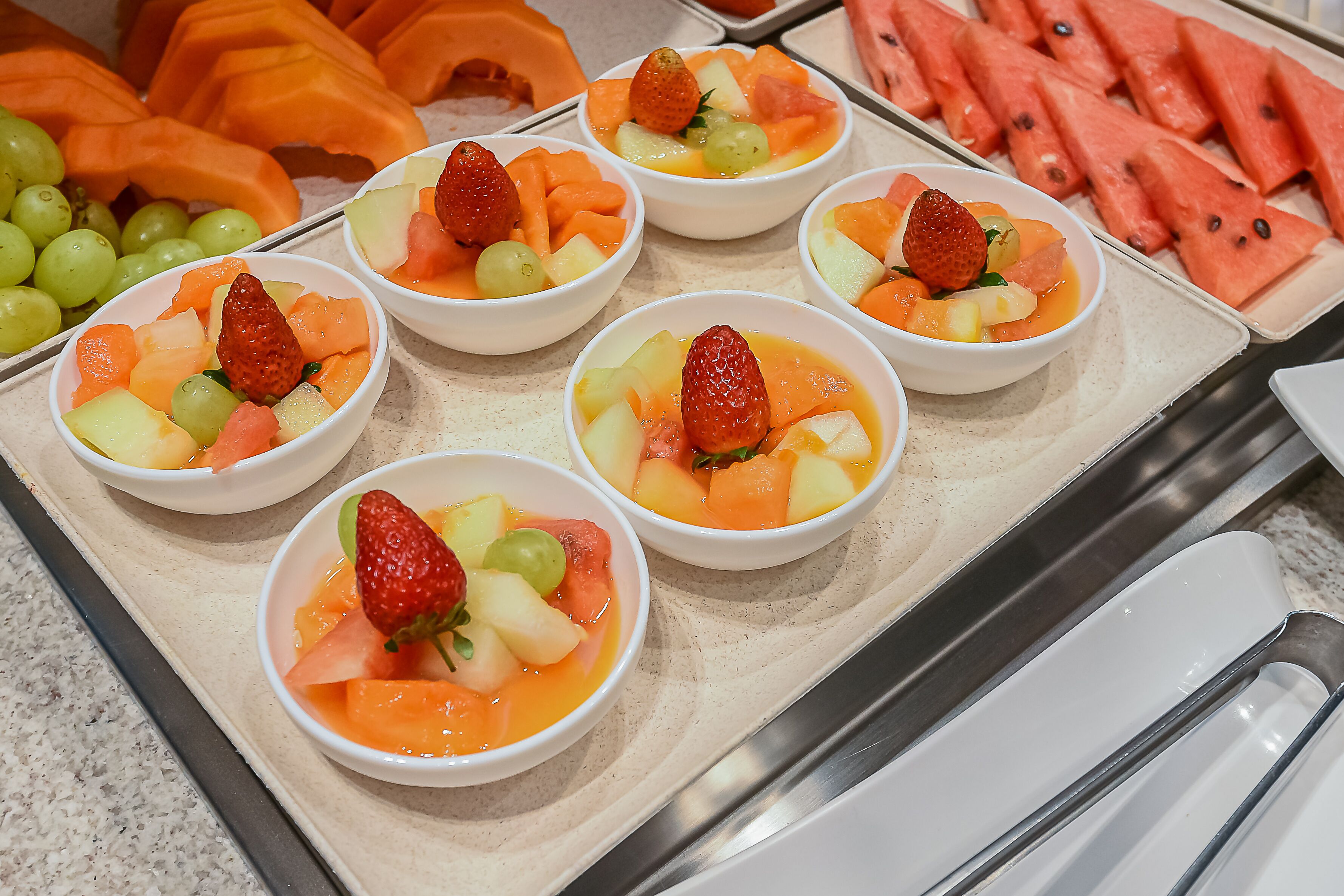 Bowls of fruit salad with strawberries and grapes.
