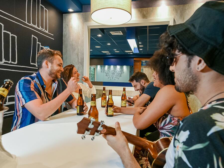 Un grupo de personas sentadas alrededor de una mesa, conversando mientras hay botellas de cerveza.