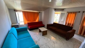 Uma sala de estar com um sofá azul, um sofá vermelho, um sofá marrom e uma mesa de centro.