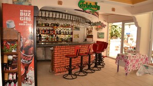 Uma área de bar com publicidade de Coca-Cola Zero, um balcão e banquetas vermelhas.