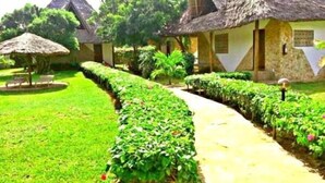 A row of thatched-roof cottages with a well-maintained garden path. - Eco Villas Watamu (Watamu)
