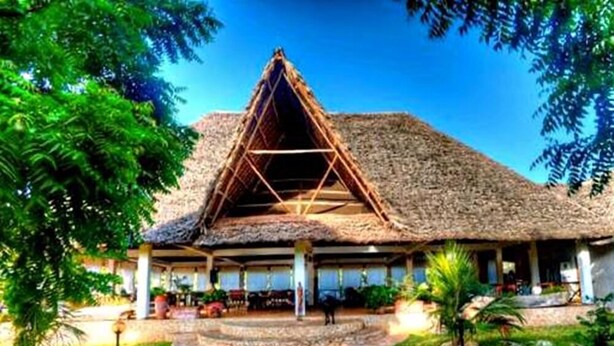 A thatched-roof building with a central open space, surrounded by a stone pathway and greenery. - Eco Villas Watamu (Watamu)