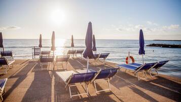 Eine Strandlounge mit Liegestühlen und Sonnenschirmen mit Blick auf das Meer.