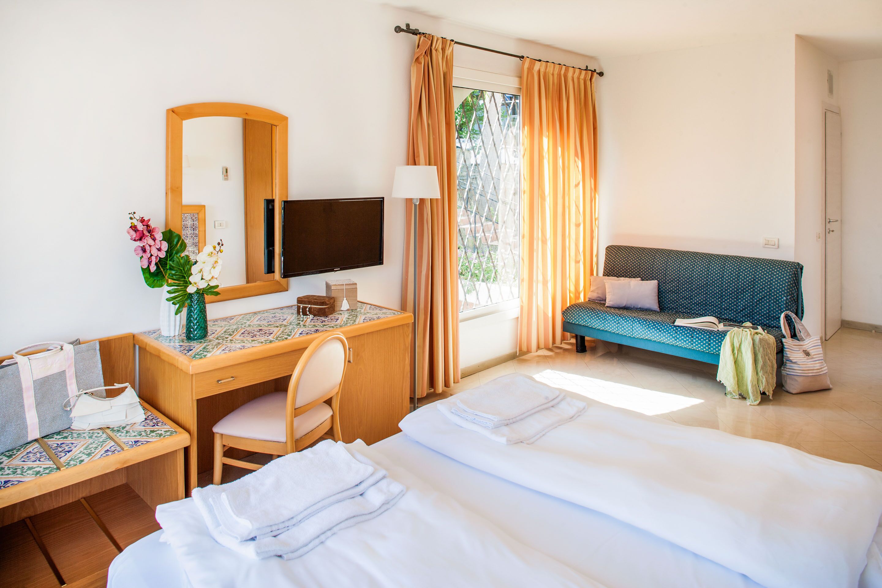 A hotel room with a bed, desk, chair, and a sofa.