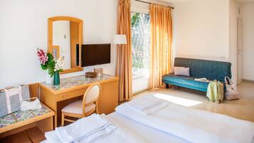 A hotel room with a bed, desk, chair, and a sofa.