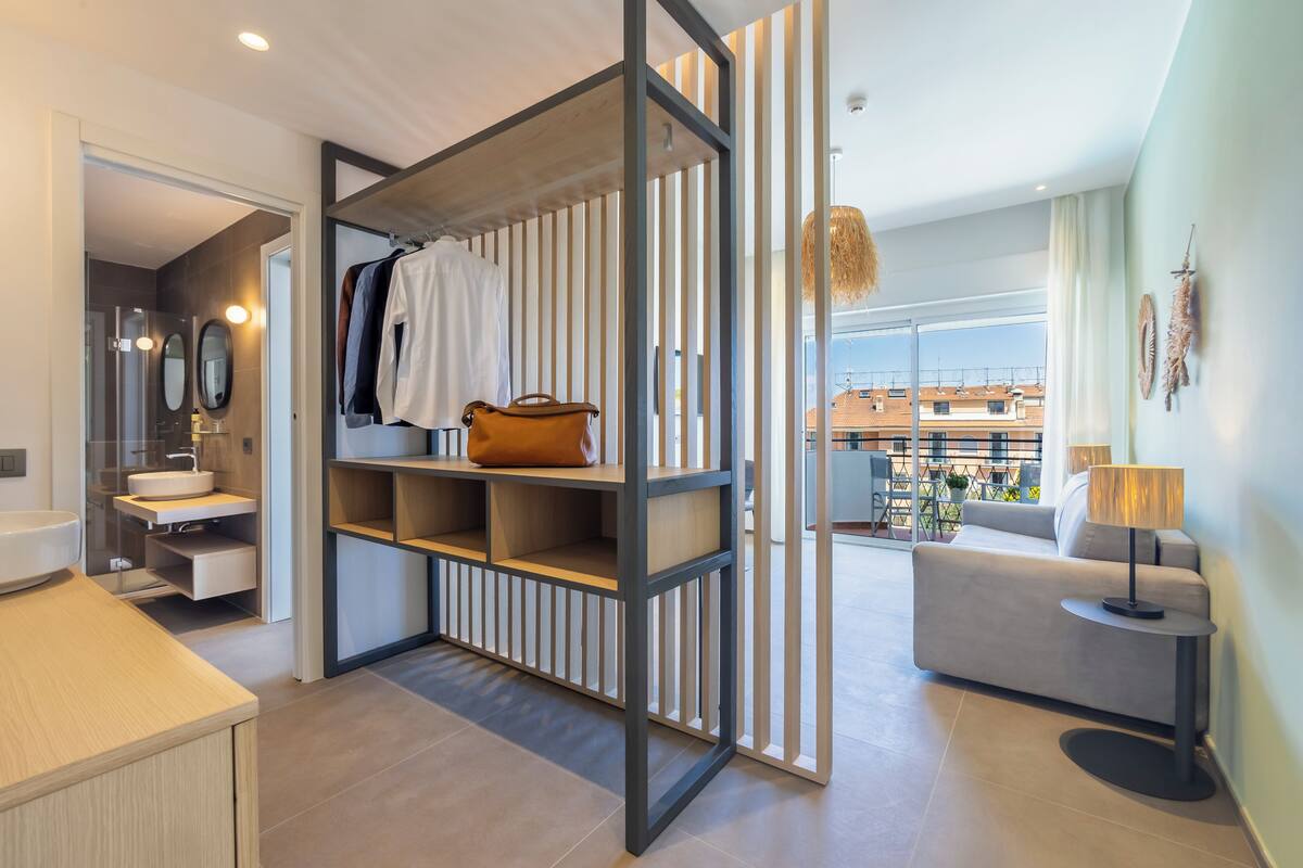 Una habitación de hotel moderna con baño, sofá, lámpara y vistas a la ciudad.