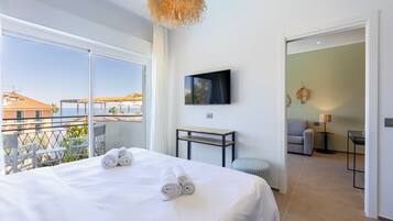Habitación de hotel con una cama grande, televisión, una mesita y vistas a la ciudad.