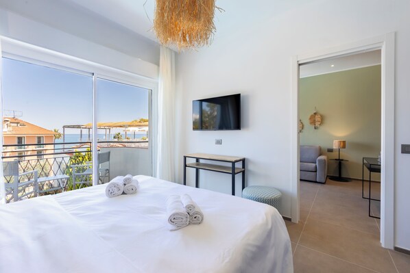 A hotel room with a large bed, a TV, a small table, and a view of the city. - Hotel Moresco (Diano Marina)
